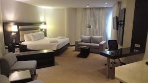 a hotel room with a bed and a couch and a desk at Rosa Bela Hotel & Convention Center in Puerto Ordaz