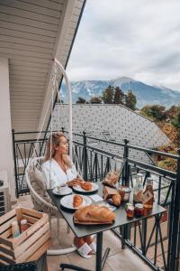 una mujer sentada en una silla en una mesa con comida en Design & Wine Vila Special Bled, en Bled