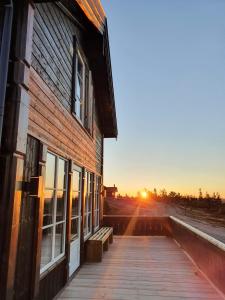 a building with a wooden walkway next to a sunset at New cabin at Lifjell perfectly located for hiking with sauna and ski-in/ski-out in Bø