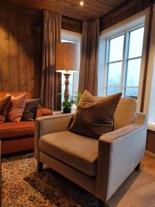 ein Wohnzimmer mit einem Stuhl, einer Lampe und Fenstern in der Unterkunft New cabin at Lifjell perfectly located for hiking with sauna and ski-in/ski-out in Bø