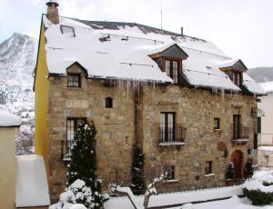 a stone building with snow on the roof at Hotel Almud in Sallent de Gállego