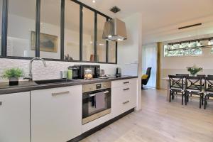 a kitchen with white cabinets and a dining room at gîte de la vache bleue en Somme in Bernaville