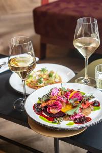 una mesa con dos platos de comida y dos copas de vino en The Florian Amsterdam Airport en Hoofddorp