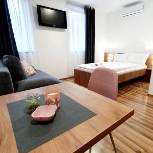 a living room with a table and a bed at Apartmani Brko in Kotor-Varoš