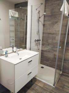 La salle de bains est pourvue d'un lavabo blanc et d'une douche. dans l'établissement APARTAMENT MARI Polanki Park, à Kołobrzeg