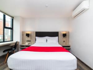 a bedroom with a large white bed with a red blanket at Hotel Nube in Puebla