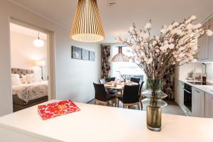 Nordica Design Residence Rovaniemi في روفانييمي: مطبخ وغرفة طعام مع طاولة مع إناء من الزهور