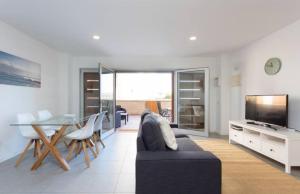 a living room with a couch and a table and a television at Modern seafront flat with a private garage in El Médano