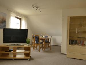 ein Wohnzimmer mit einem TV und einem Tisch mit Stühlen in der Unterkunft Cozy Apartment located in Rovershagen with Garden in Rövershagen