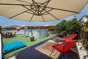 蒂納霍的住宿－La Malvasía，庭院配有红色椅子和遮阳伞。