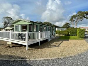 a green and white house with a porch at Happy Days Holiday Home Whithorn2 in Newton Stewart