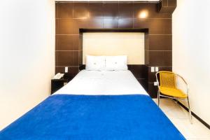 1 dormitorio con 1 cama y 1 silla amarilla en Hotel Kapu, en Puebla