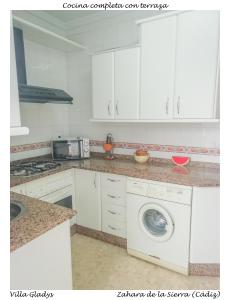 cocina con armarios blancos y lavadora en CASA GLADYS, en Zahara de la Sierra