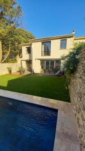 a house with a swimming pool in front of a yard at La Closerie du Château in Uzès