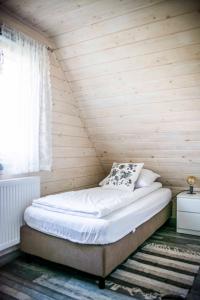a bed in a room with a wooden wall at WIEJSKI RELAKS in Czarny Dunajec