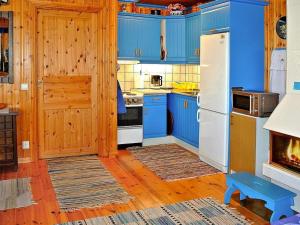 La cuisine est équipée de placards bleus et d'un réfrigérateur blanc. dans l'établissement 2 person holiday home in BENGTSFORS, à Bengtsfors