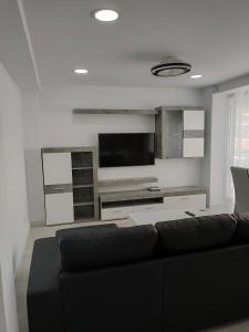 een woonkamer met een zwarte bank en een flatscreen-tv bij Maya in Era de Soler