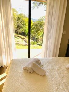 a bed with two towels on it with a window at CasAlta Pousada in Bento Gonçalves