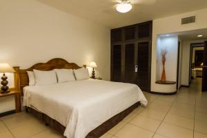 um quarto com uma grande cama branca num quarto em Hotel Soleil Pacifico em Chulamar