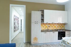 una cocina con armarios blancos y fregadero en MERCATO55, en Castellaneta