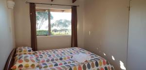 a small bedroom with a bed with a window at Hot Water Beach Cottage in Hotwater Beach