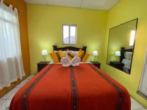a large red bed in a room with yellow walls at Hotel Los Angeles Panajachel in Panajachel