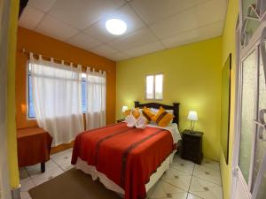 a bedroom with a bed with orange and yellow walls at Hotel Los Angeles Panajachel in Panajachel