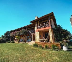 a large house with a porch and a lawn at Pousada Capitão Cook a 200 m do centro in Praia do Rosa