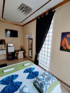 a bedroom with a bed with blue pillows and a window at Pousada AM PM in Campo Grande