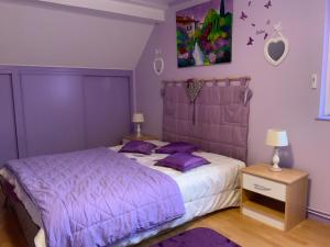 sypialnia z fioletowym łóżkiem z fioletowymi poduszkami w obiekcie le nid fleuri de Cravanche w mieście Cravanche