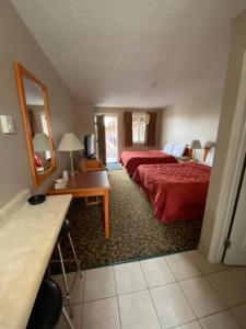 a hotel room with two beds and a desk and a mirror at Aspen Motor Inn in Drayton Valley