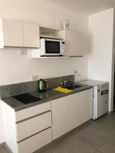 a white kitchen with a sink and a microwave at Departamento Studio in Corrientes