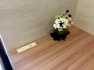 a vase of flowers on a floor next to a clock at Cabin & Capsule Hotel J-SHIP Osaka Namba in Osaka
