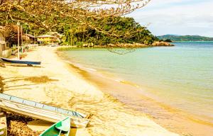 una playa de arena junto a un cuerpo de agua en Pousada Casa do Oscar, en Governador Celso Ramos