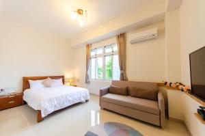 ein Schlafzimmer mit einem Bett, einem Sofa und einem TV in der Unterkunft Long Forest Homestay in Luodong