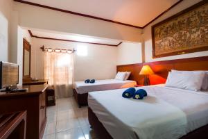 a hotel room with two beds and a television at Mahajaya Hotel Denpasar in Denpasar