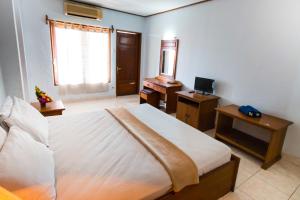 a bedroom with a bed and a desk and a television at Mahajaya Hotel Denpasar in Denpasar