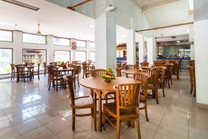 a restaurant with wooden tables and chairs and windows at Mahajaya Hotel Denpasar in Denpasar