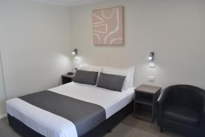 ein Schlafzimmer mit einem Bett und einem schwarzen Stuhl in der Unterkunft Ryley Motor Inn in Wangaratta