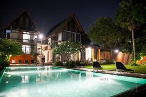 a swimming pool in front of a house at night at iuDia Hotel in Phra Nakhon Si Ayutthaya