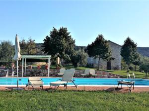 two chairs and an umbrella next to a swimming pool at Belvilla by OYO Appartamento Dante in Serre di Rapolano