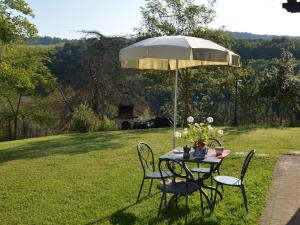a table and chairs under an umbrella in a field at Belvilla by OYO Appartamento Dante in Serre di Rapolano