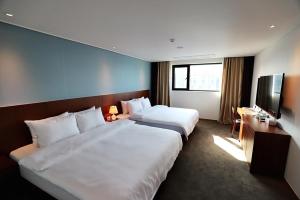 Sea Moon Tourist Hotel في انشيون: غرفة فندقية بسريرين وتلفزيون بشاشة مسطحة