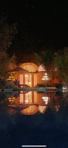 a person sitting under an umbrella near a swimming pool at night at Cabañas Caballieri in Pisco Elqui