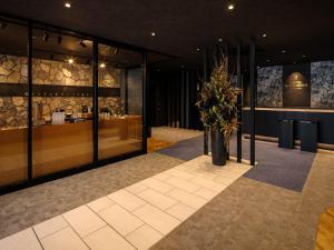 a lobby with a vase of flowers on the floor at Hotel Act Garden HAMAMATSU in Hamamatsu