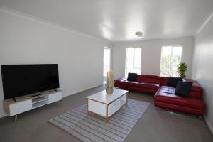 a living room with a red couch and a flat screen tv at Wagga Apartments #8 in Wagga Wagga