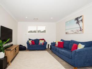 a living room with two blue couches and a flat screen tv at Havenwood - Pet Friendly - Spa & Community Pool in Callala Beach