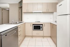 a kitchen with white cabinets and white appliances at Hume Serviced Apartments in Adelaide