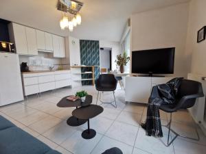 a living room with a couch and a table and a kitchen at CÔTÉ GARE - Gare - Centre-ville - Parking - Netflix - Wifi - Disney+ - Terrasse in Annecy