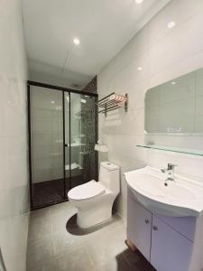 a white bathroom with a toilet and a sink at 站前夥伴旅宿 in Hualien City